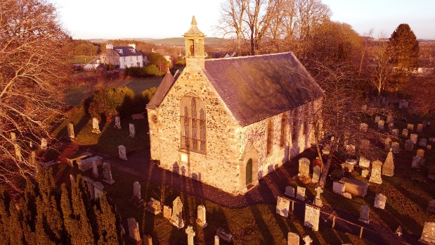 St Michael's Church from above at sunset, its bellcote and slate roof rising above the surrounding graveyard